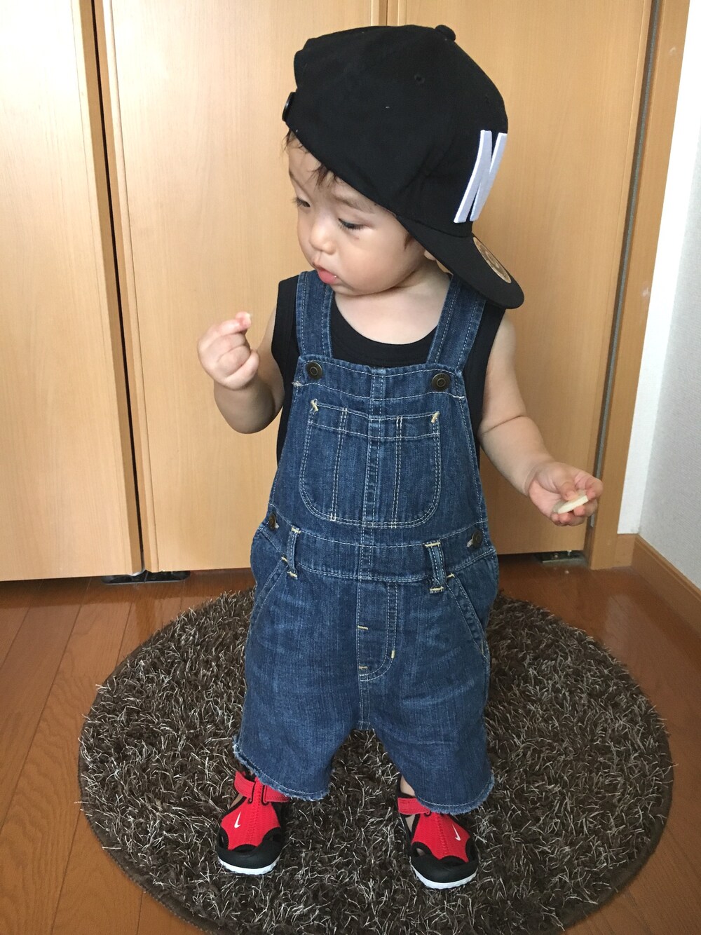 ブラック系のタンクトップ、ブルー系のサロペット/オーバーオール、レッド系のサンダルを着用したキッズの夏コーディネートの1枚目の写真