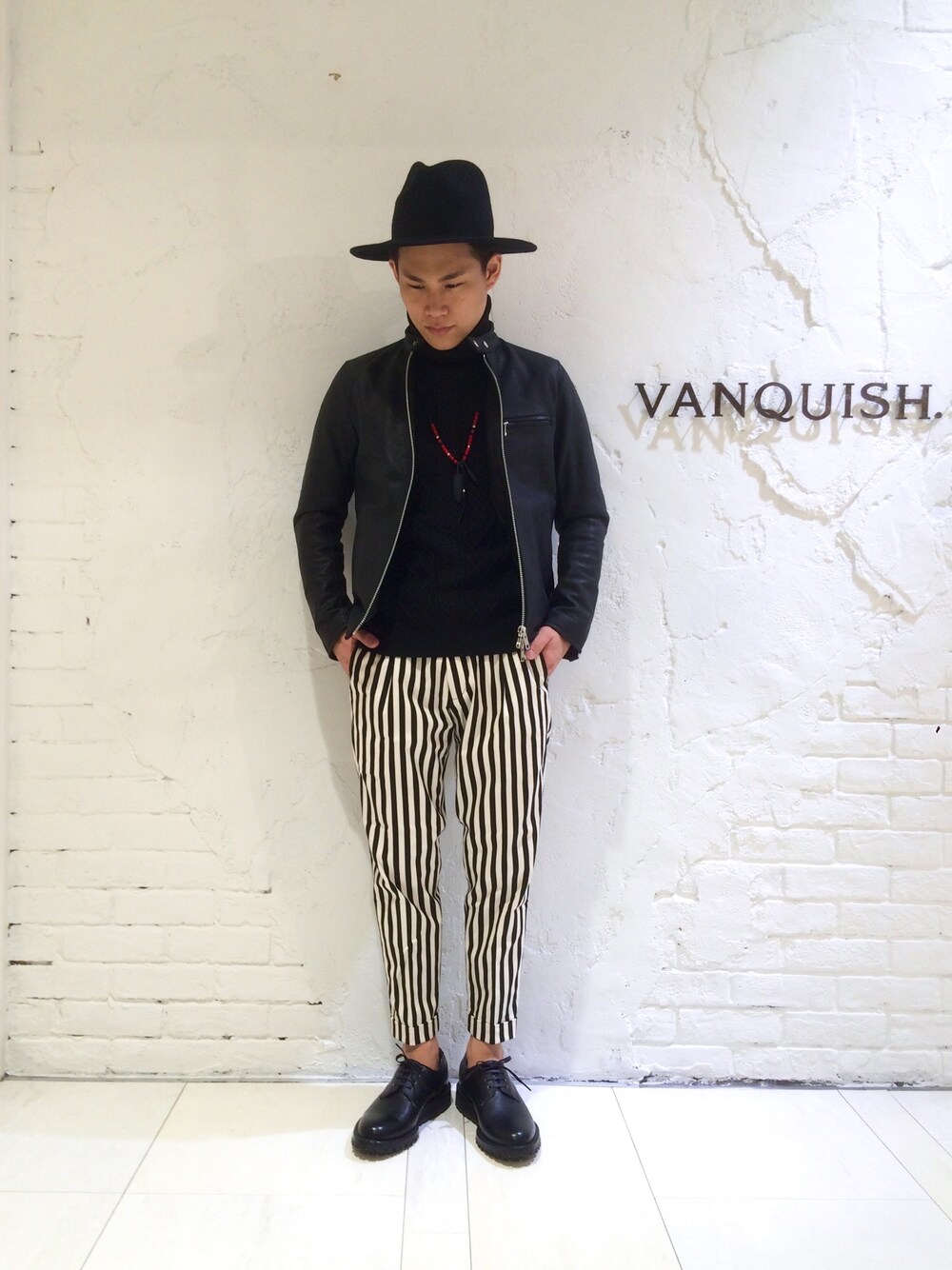 「VANQUISH、ブラック、モノトーン、レザージャケット、シングルライダース、タートルネック、ニット、ストライプ、フェザー、オックスフォードシューズ」｜「VANQUISHのカラーミドルブリムハット（ハット、ブラック系）」を使った、高村 拓弥さん（メンズ・170cm）の秋コーディネートの1枚目の写真