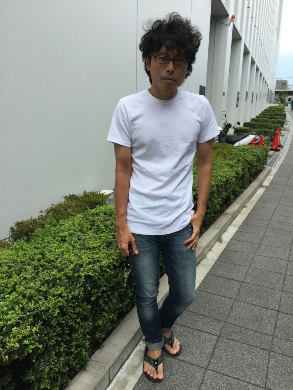 ホワイト系のTシャツ/カットソー、ブルー系のデニムパンツ、ブラック系のビーチサンダルを着用したメンズの夏コーディネートの1枚目の写真