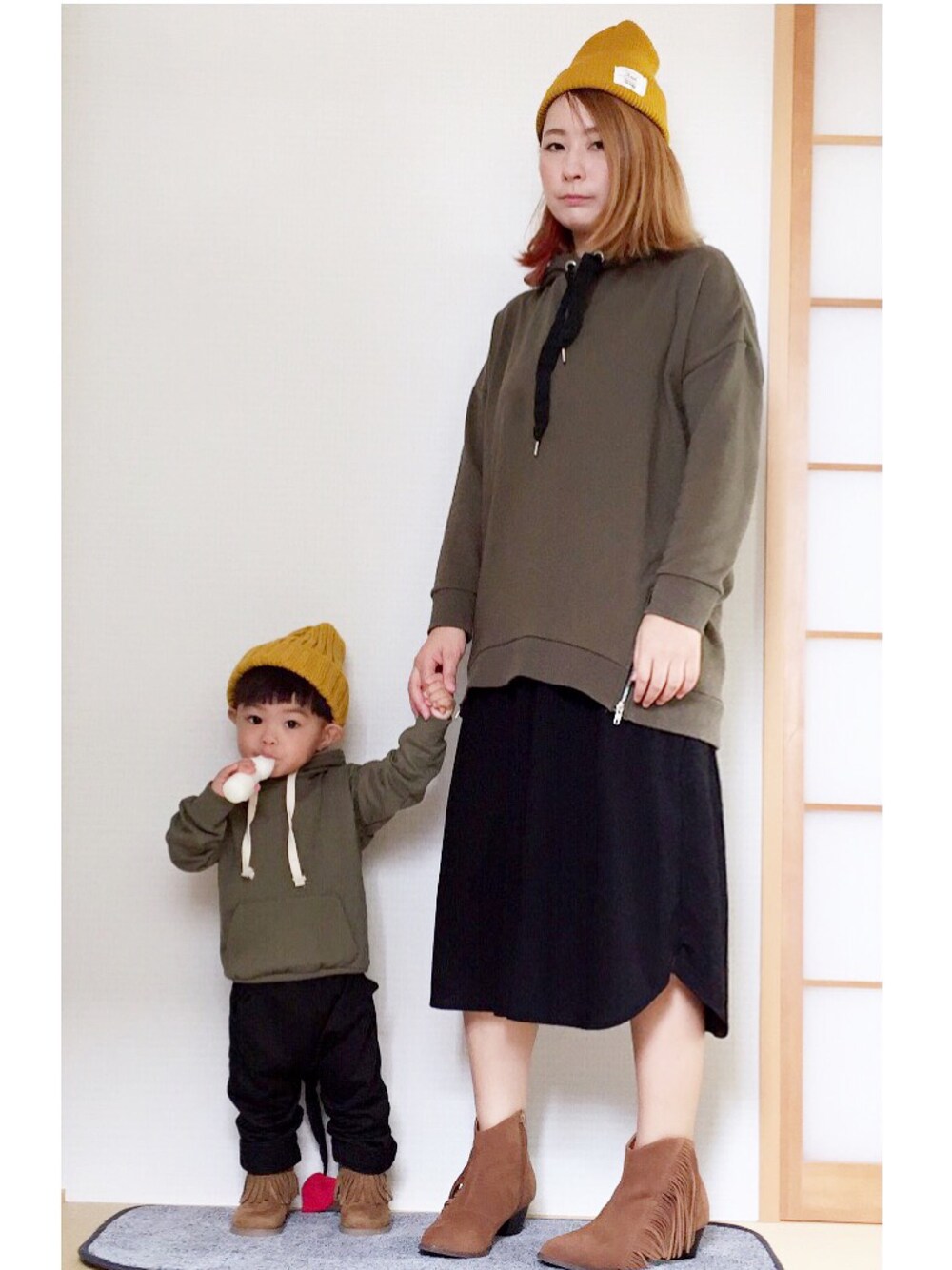 ブラック系のワンピース、ブラウン系のブーツ、グリーン系のパーカーを着用したキッズの秋コーディネートの1枚目の写真