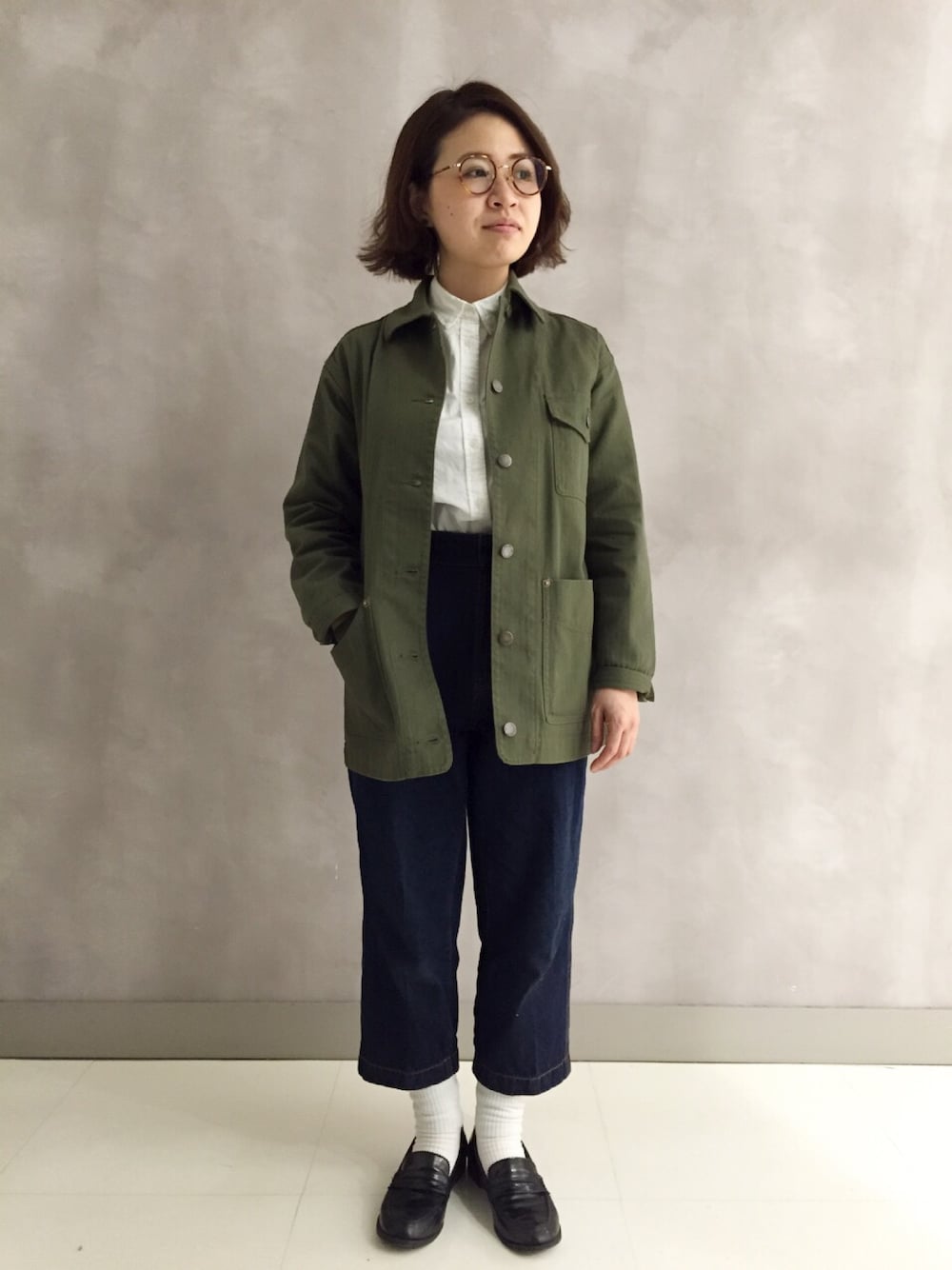 グリーン系のカバーオール、ブルー系のデニムパンツ、ブラック系のシューズを着用したレディースの冬コーディネートの1枚目の写真