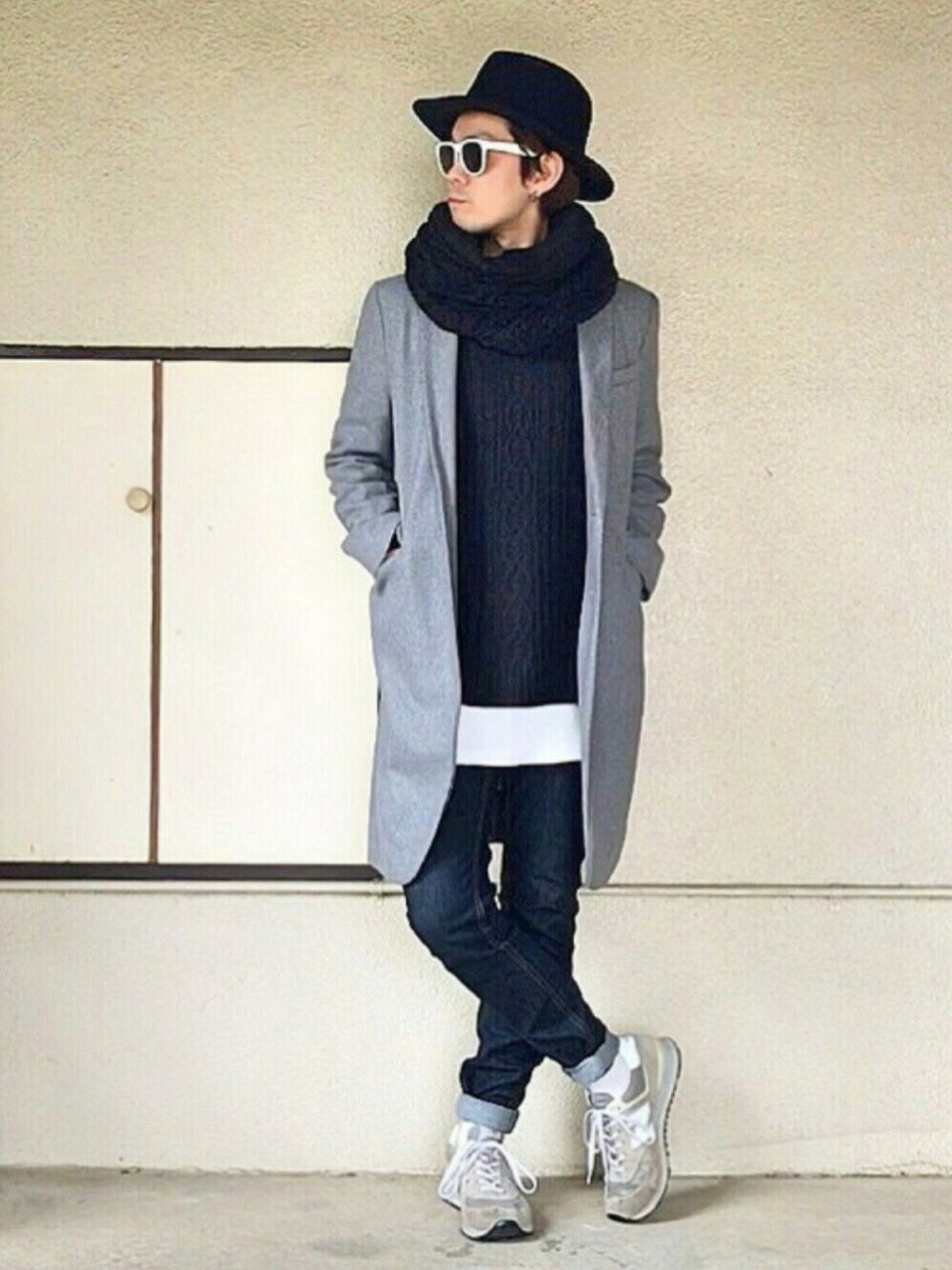 グレー系のチェスターコート、ブラック系のニット/セーター、ホワイト系のTシャツ/カットソーを着用したメンズの秋コーディネートの1枚目の写真