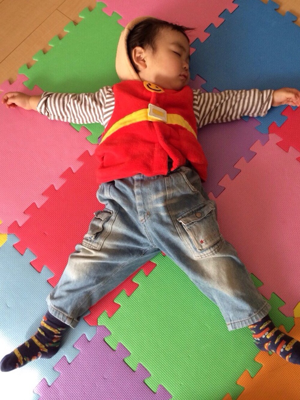 レッド系のベスト、ホワイト系のTシャツ/カットソー、ブルー系のデニムパンツを着用したキッズの冬コーディネートの1枚目の写真