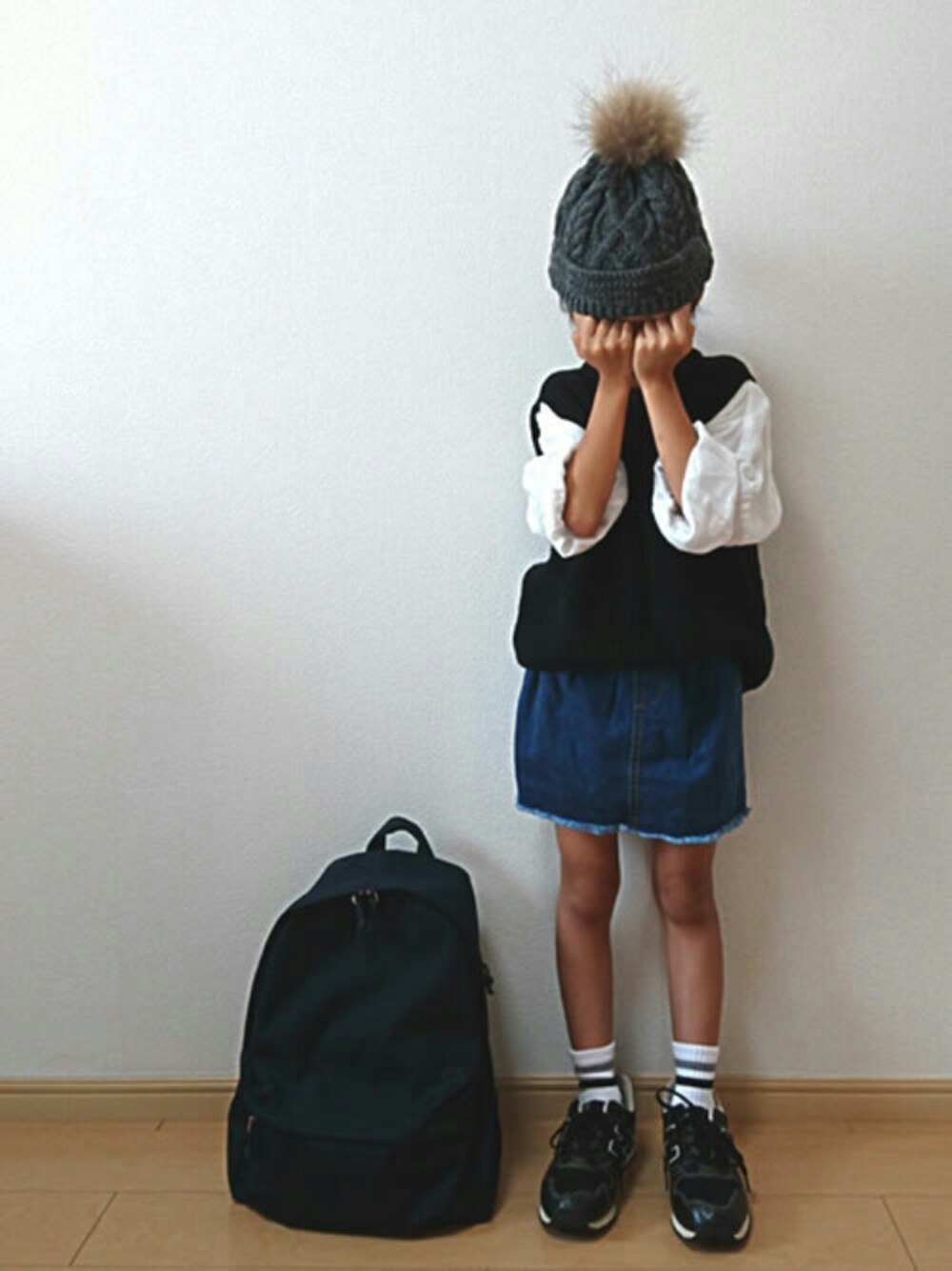 ブルー系のデニムスカート、ブラック系のバックパック/リュック、ブラック系のスニーカーを着用したキッズの秋コーディネートの1枚目の写真