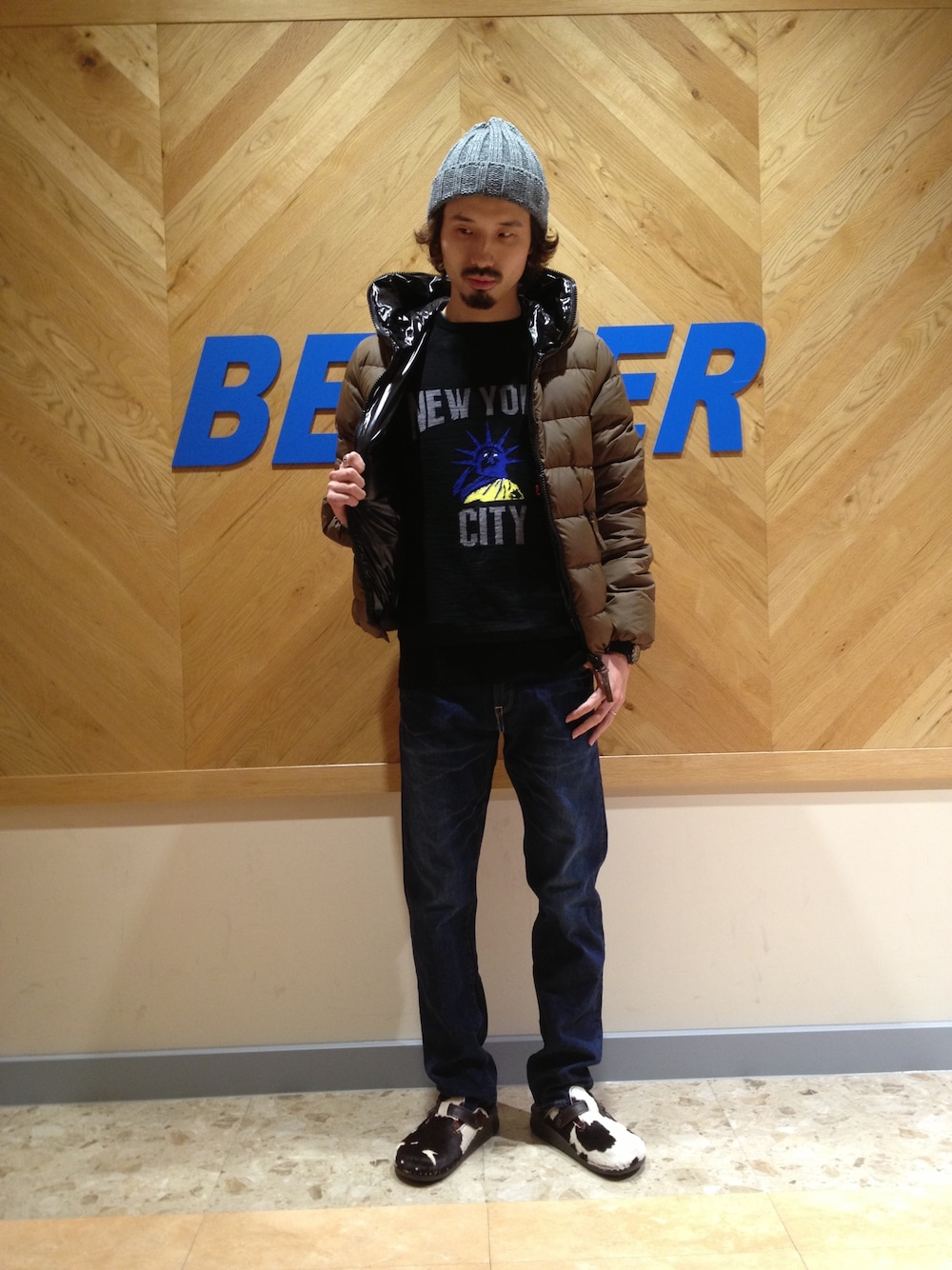 グリーン系のダウンジャケット/コート、ブラック系のニット/セーター、ブルー系のデニムパンツを着用したメンズの秋コーディネートの1枚目の写真