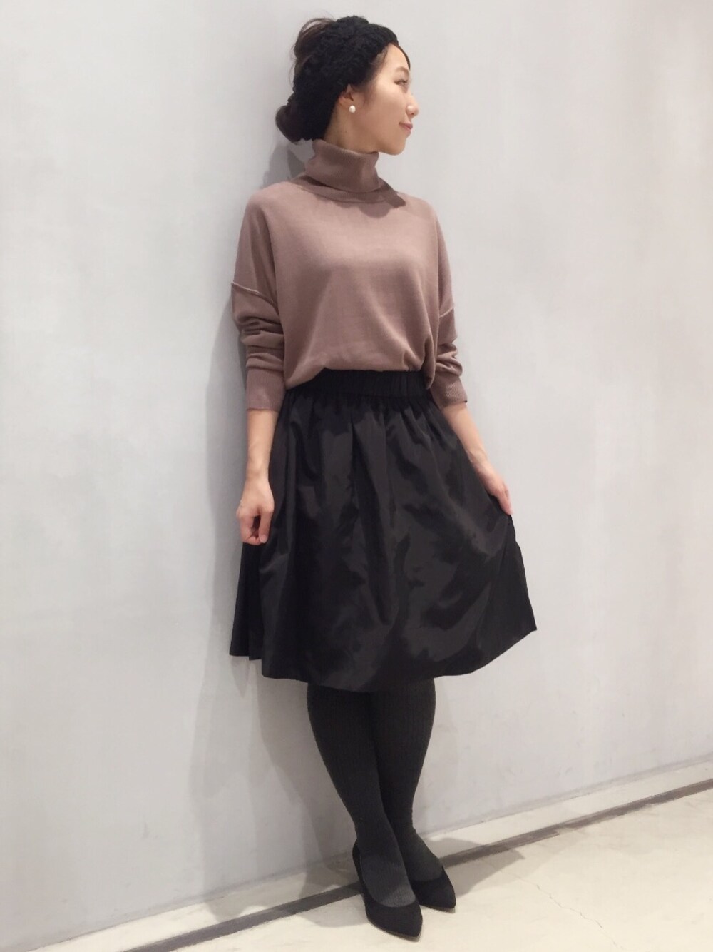 ブラック系のスカート、ベージュ系のニット/セーター、ブラック系のパンプスを着用したレディースの秋コーディネートの1枚目の写真