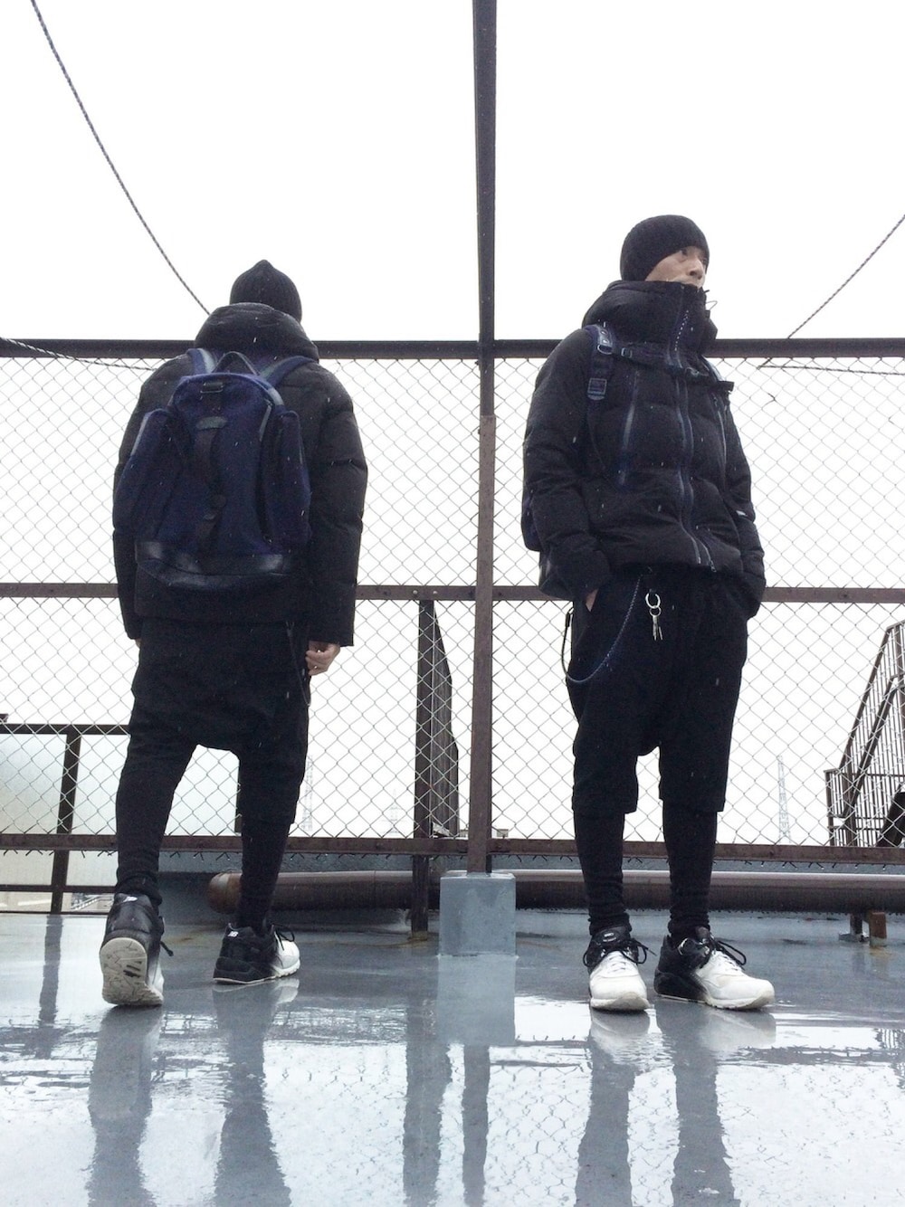 ブラック系のダウンジャケット/コート、ブラック系のTシャツ/カットソー、ブルー系のバックパック/リュックを着用したメンズの秋コーディネートの1枚目の写真