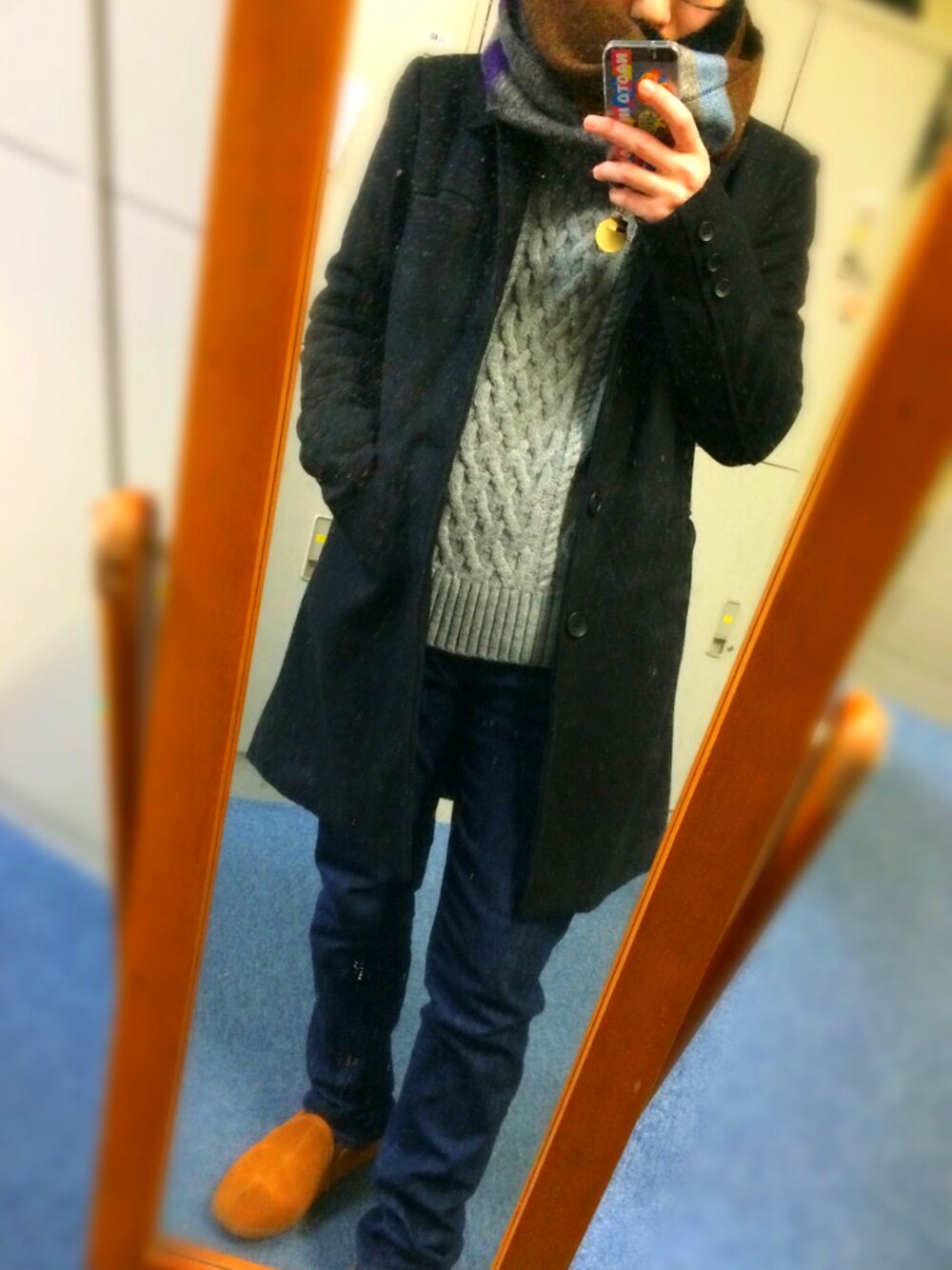 グレー系のニット/セーター、ブラック系のチェスターコート、ブラウン系のスリッポンを着用したメンズの冬コーディネートの1枚目の写真