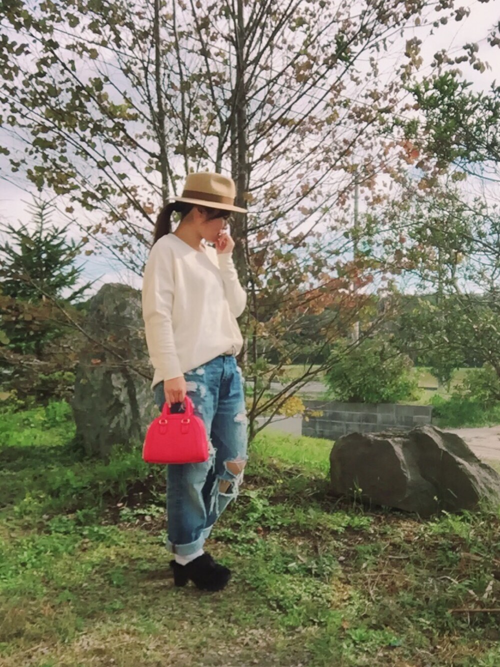 ホワイト系のTシャツ/カットソー、ブルー系のデニムパンツ、レッド系のボストンバッグを着用したレディースの秋コーディネートの1枚目の写真