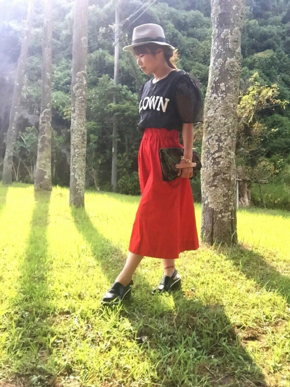 ブラック系のシャツ/ブラウス、レッド系のスカート、その他のクラッチバッグを着用したレディースの秋コーディネートの1枚目の写真