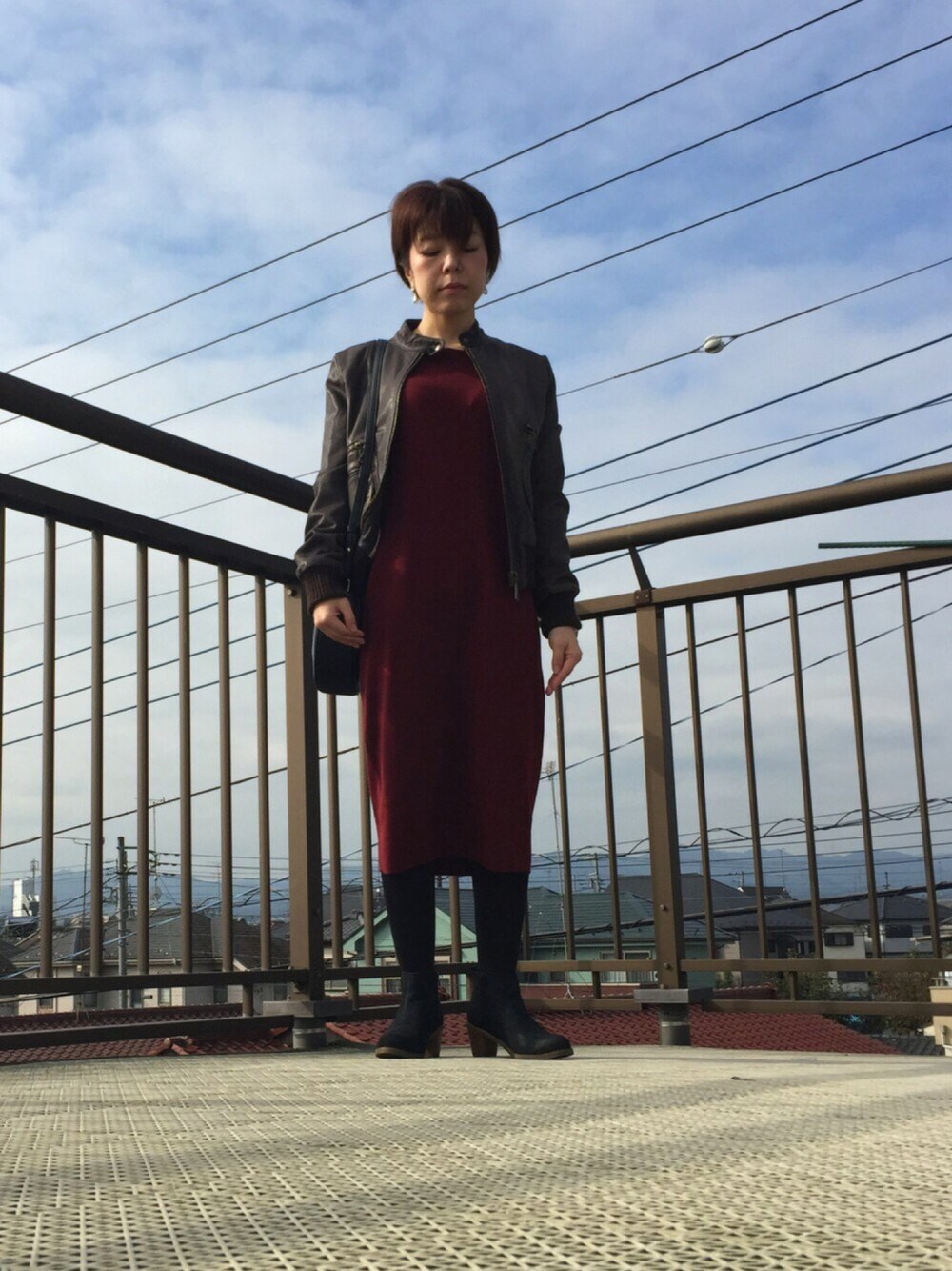 ブラウン系のライダースジャケット、レッド系のワンピース、ブラック系のショルダーバッグを着用したレディースの秋コーディネートの1枚目の写真