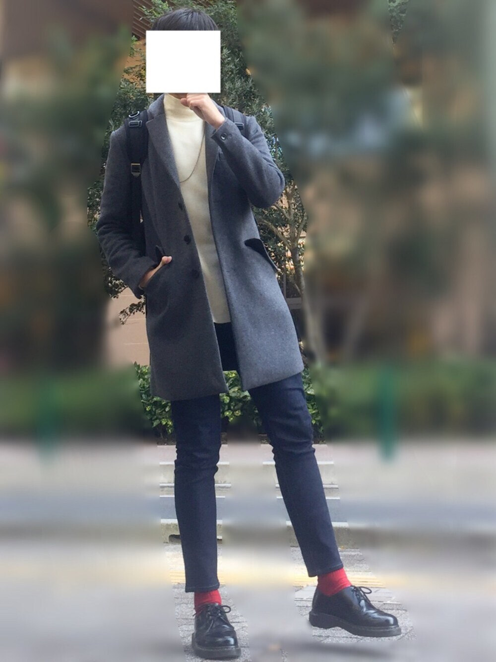 グレー系のチェスターコート、ホワイト系のニット/セーター、ブルー系のデニムパンツを着用したメンズの秋コーディネートの1枚目の写真