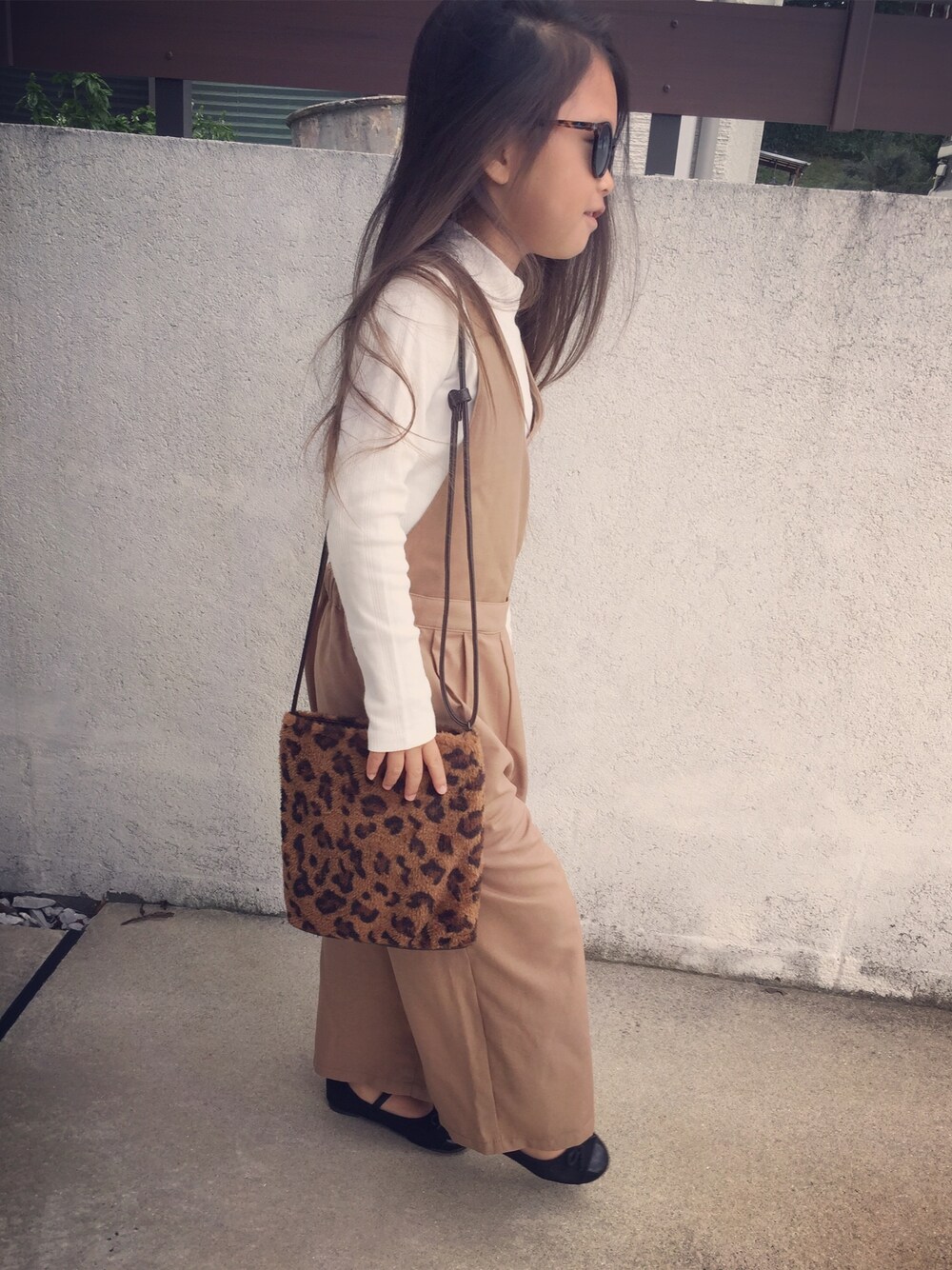 ブラウン系のサロペット/オーバーオール、ブラウン系のバッグ、ホワイト系のTシャツ/カットソーを着用したキッズの秋コーディネートの1枚目の写真