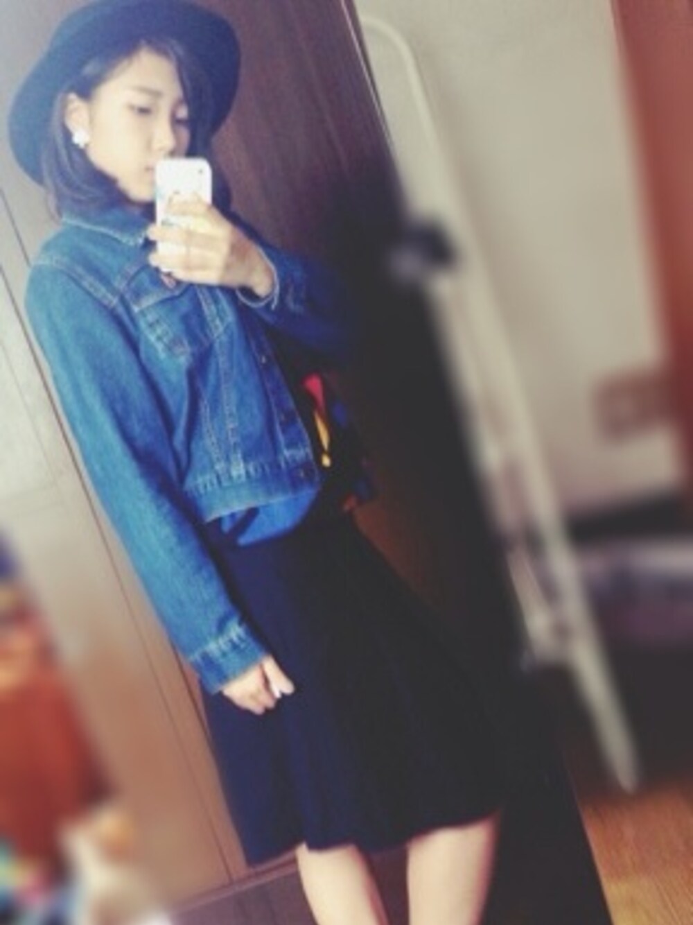 ブルー系のデニムジャケット、ブラック系のニット/セーター、ホワイト系のクラッチバッグを着用したレディースの秋コーディネートの1枚目の写真