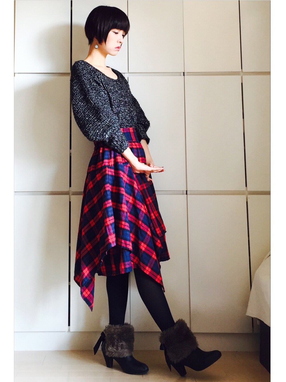 レッド系のスカート、ブラック系のニット/セーターを着用したレディースの秋コーディネートの1枚目の写真