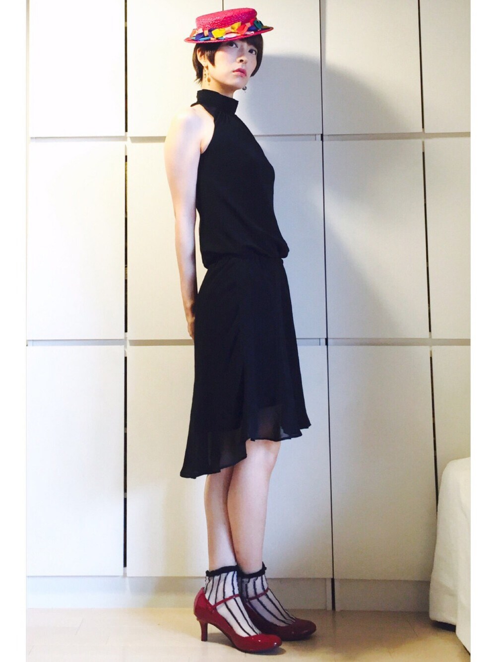 レッド系のパンプス、ブラック系のワンピース、ピンク系のハットを着用したレディースの夏コーディネートの1枚目の写真