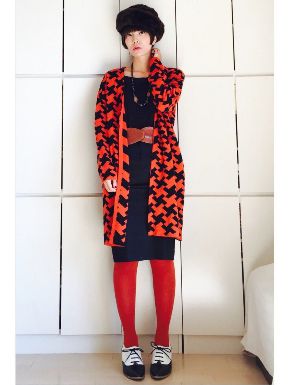 オレンジ系のカーディガン/ボレロ、ブラック系のスカート、ホワイト系のドレスシューズを着用したレディースの秋コーディネートの1枚目の写真