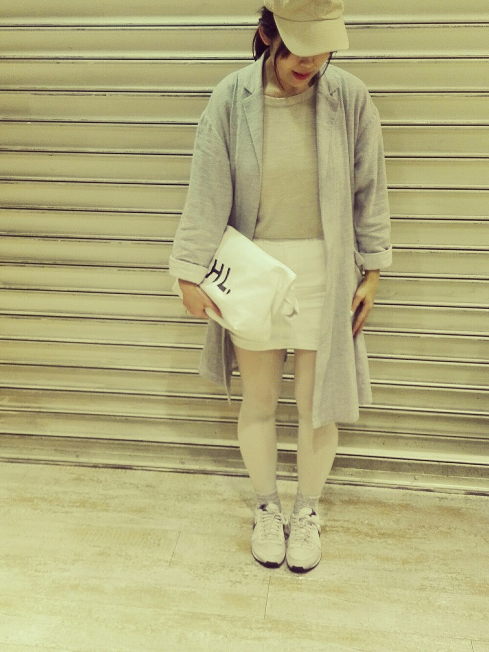 グレー系のスニーカー、ホワイト系のスカート、グレー系のカバーオールを着用したレディースの春コーディネートの1枚目の写真