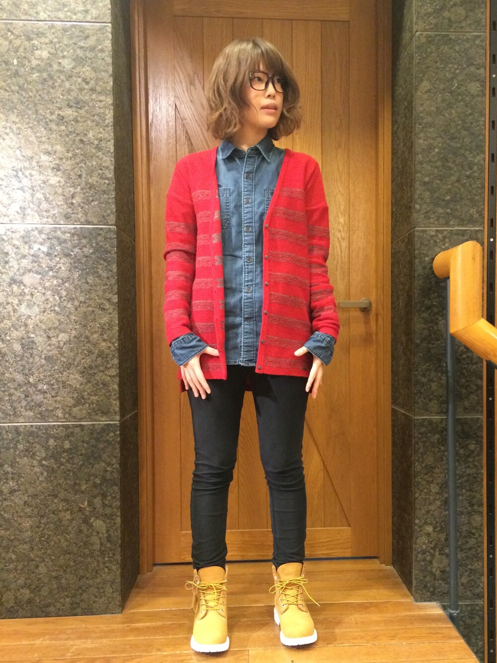 ベージュ系のスニーカー、レッド系のカーディガン/ボレロ、ブラック系のデニムパンツを着用したレディースの冬コーディネートの1枚目の写真