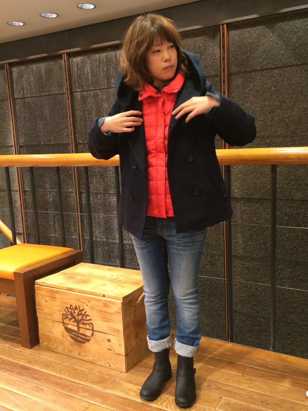 ブルー系のデニムパンツ、ピンク系のダウンベスト、ブラック系のブーツを着用したレディースの冬コーディネートの1枚目の写真