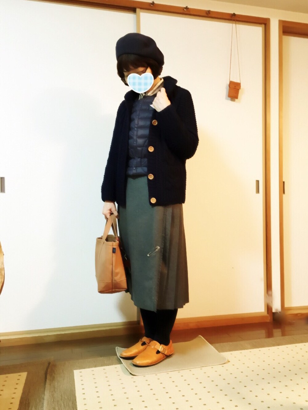 ブルー系のベスト、ブルー系のニット/セーター、グレー系のスカートを着用したレディースの冬コーディネートの1枚目の写真