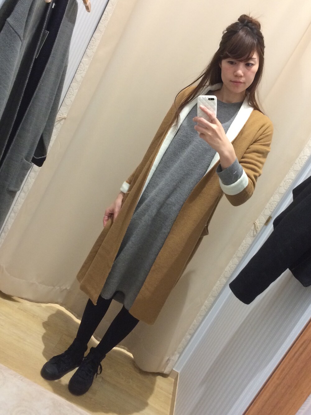 グレー系のワンピース、ベージュ系のカーディガン/ボレロ、ブラック系のスニーカーを着用したレディースの冬コーディネートの1枚目の写真