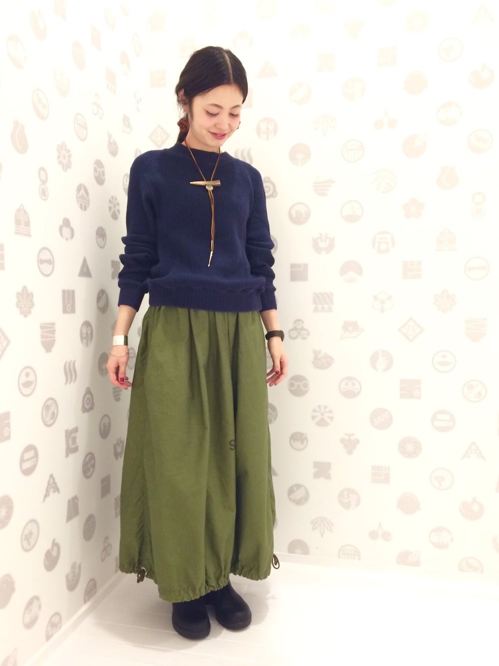 グリーン系のスカート、ブルー系のスウェット、ブラック系のレインシューズを着用したレディースの秋コーディネートの1枚目の写真