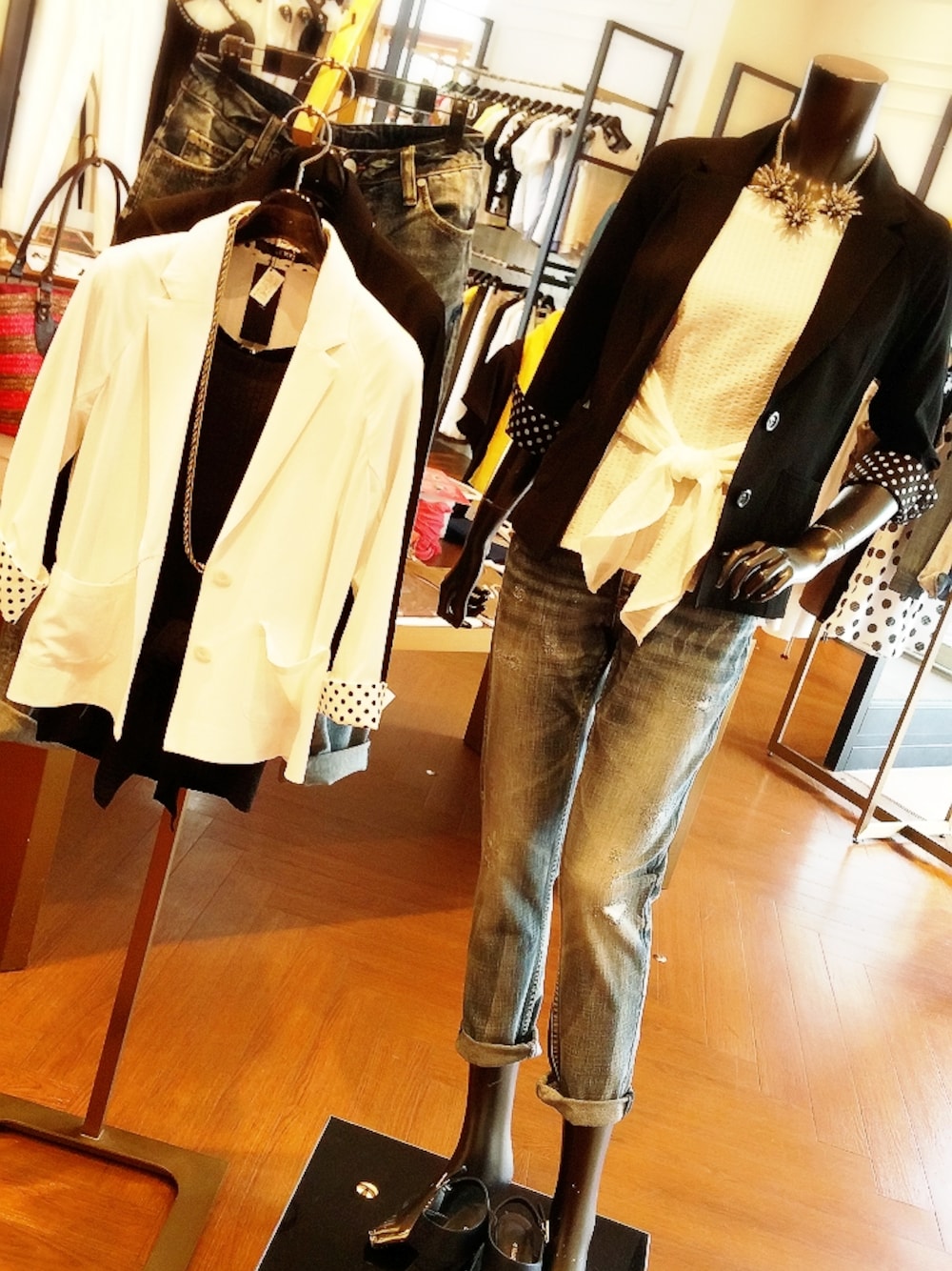 ブラック系のテーラードジャケット、ブルー系のパンツ、ホワイト系のトップスを着用したレディースの夏コーディネートの1枚目の写真