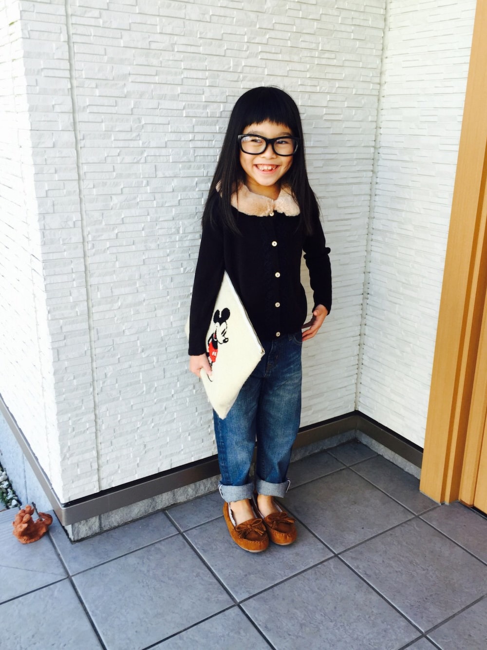 ブラック系のニット/セーター、その他のクラッチバッグ、ブルー系のデニムパンツを着用したキッズの冬コーディネートの1枚目の写真