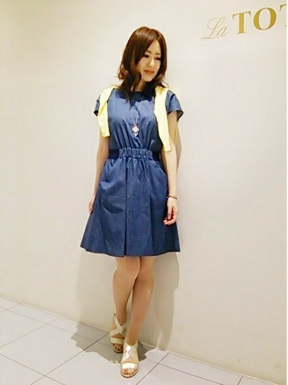 ブルー系のワンピース、ゴールド系のサンダル、イエロー系のカーディガン/ボレロを着用したレディースの夏コーディネートの1枚目の写真