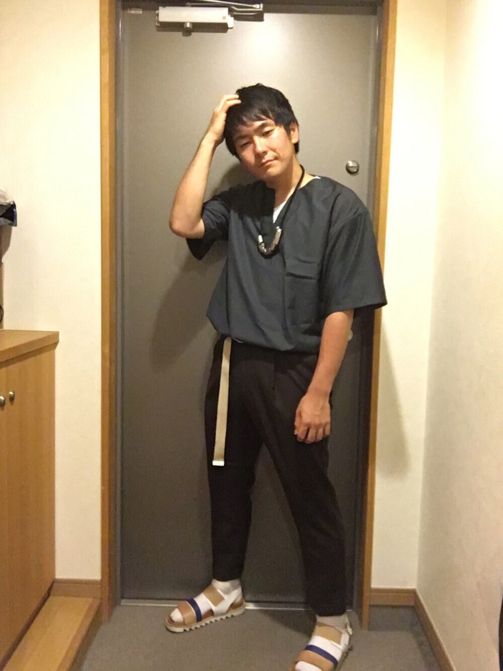 グレー系のTシャツ/カットソー、レッド系のその他パンツ、ホワイト系のサンダルを着用したメンズの秋コーディネートの1枚目の写真