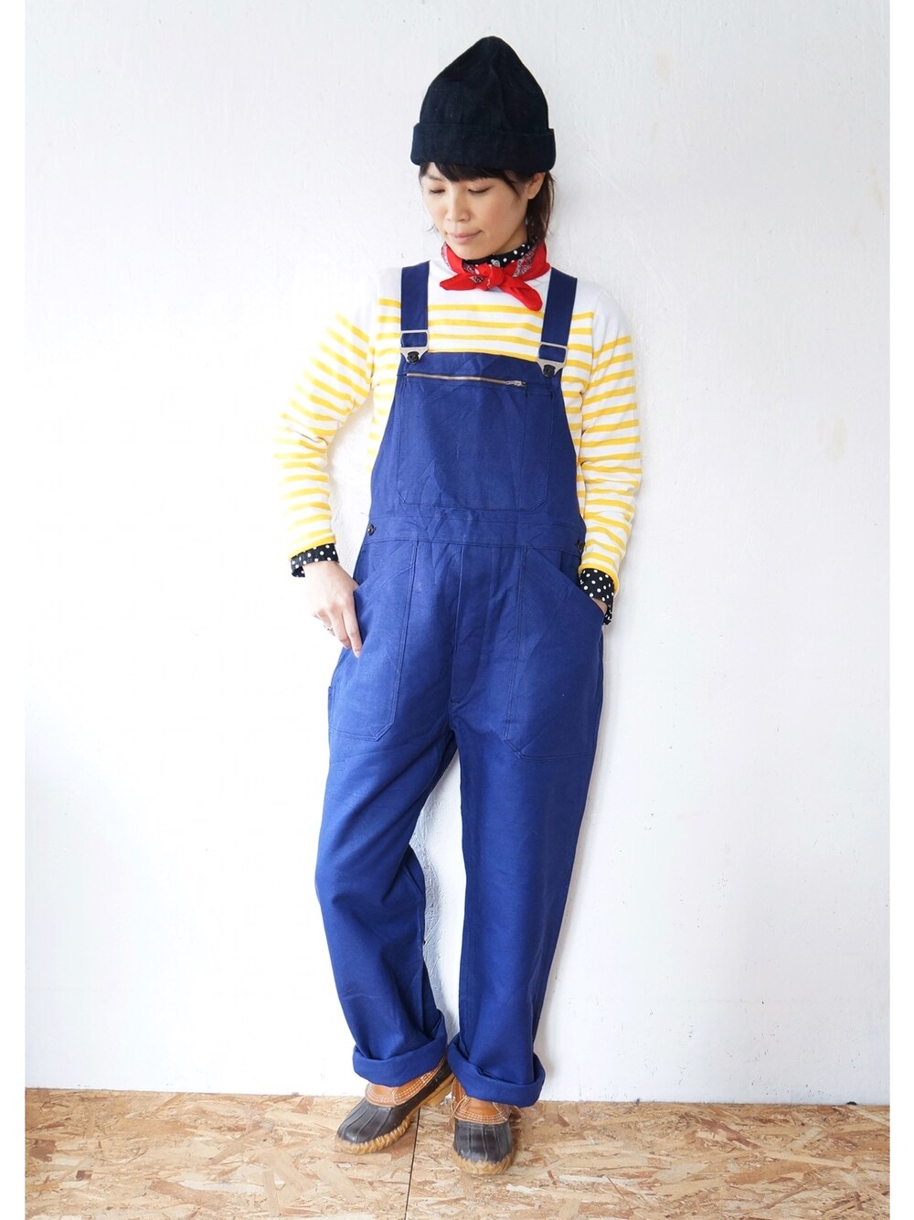 イエロー系のTシャツ/カットソー、ブルー系のサロペット/オーバーオール、ブラウン系のレインシューズを着用したレディースの冬コーディネートの1枚目の写真