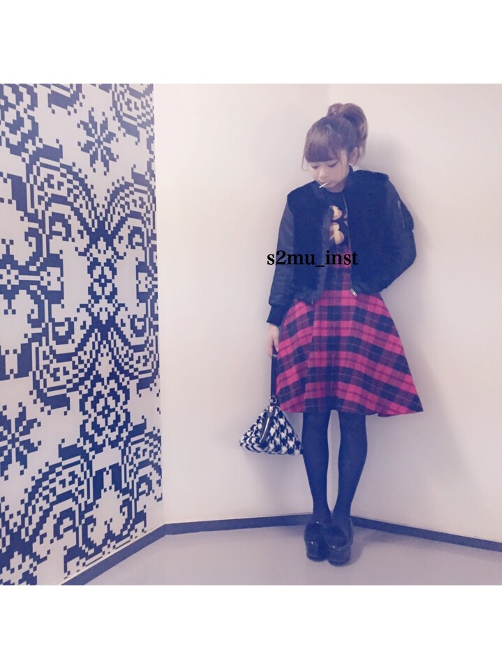 レッド系のスカート、ブラック系のハンドバッグ、ブラック系のブルゾンを着用したレディースの冬コーディネートの1枚目の写真