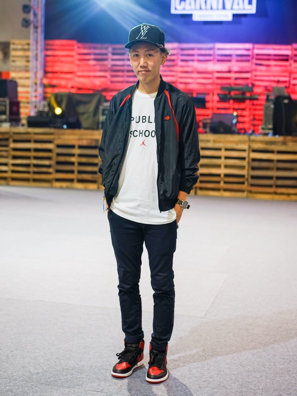 ブラック系のナイロンジャケット、レッド系のスニーカー、ブラック系のキャップを着用したメンズの秋コーディネートの1枚目の写真