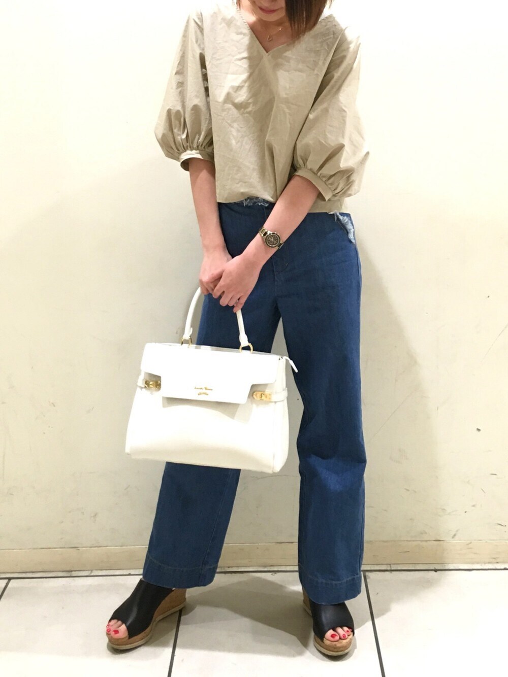 ホワイト系のハンドバッグ、ブルー系のデニムパンツ、ブラック系のサンダルを着用したレディースの夏コーディネートの1枚目の写真