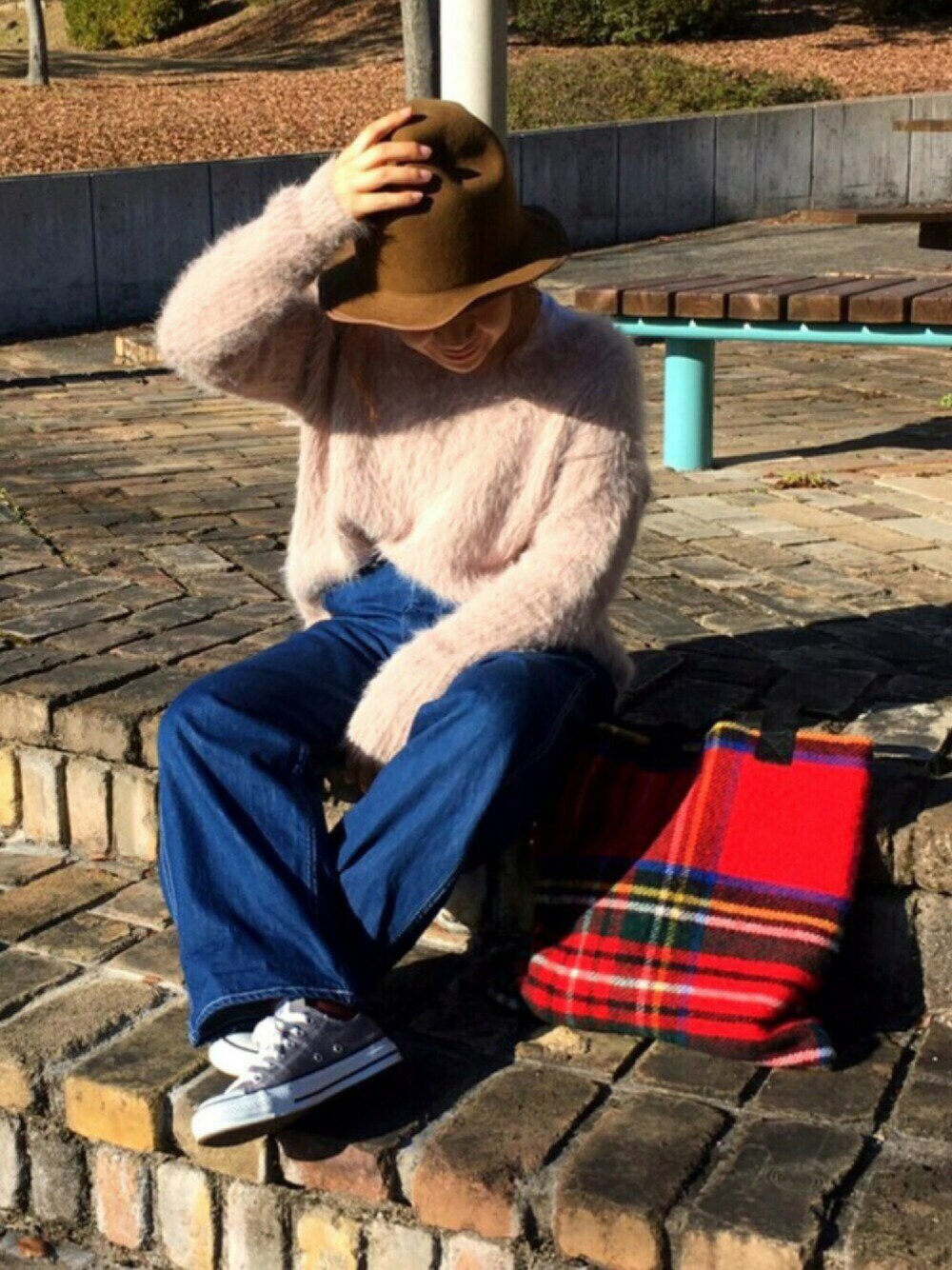 ベージュ系のニット/セーター、ブルー系のその他パンツ、レッド系のトートバッグを着用したレディースの冬コーディネートの1枚目の写真