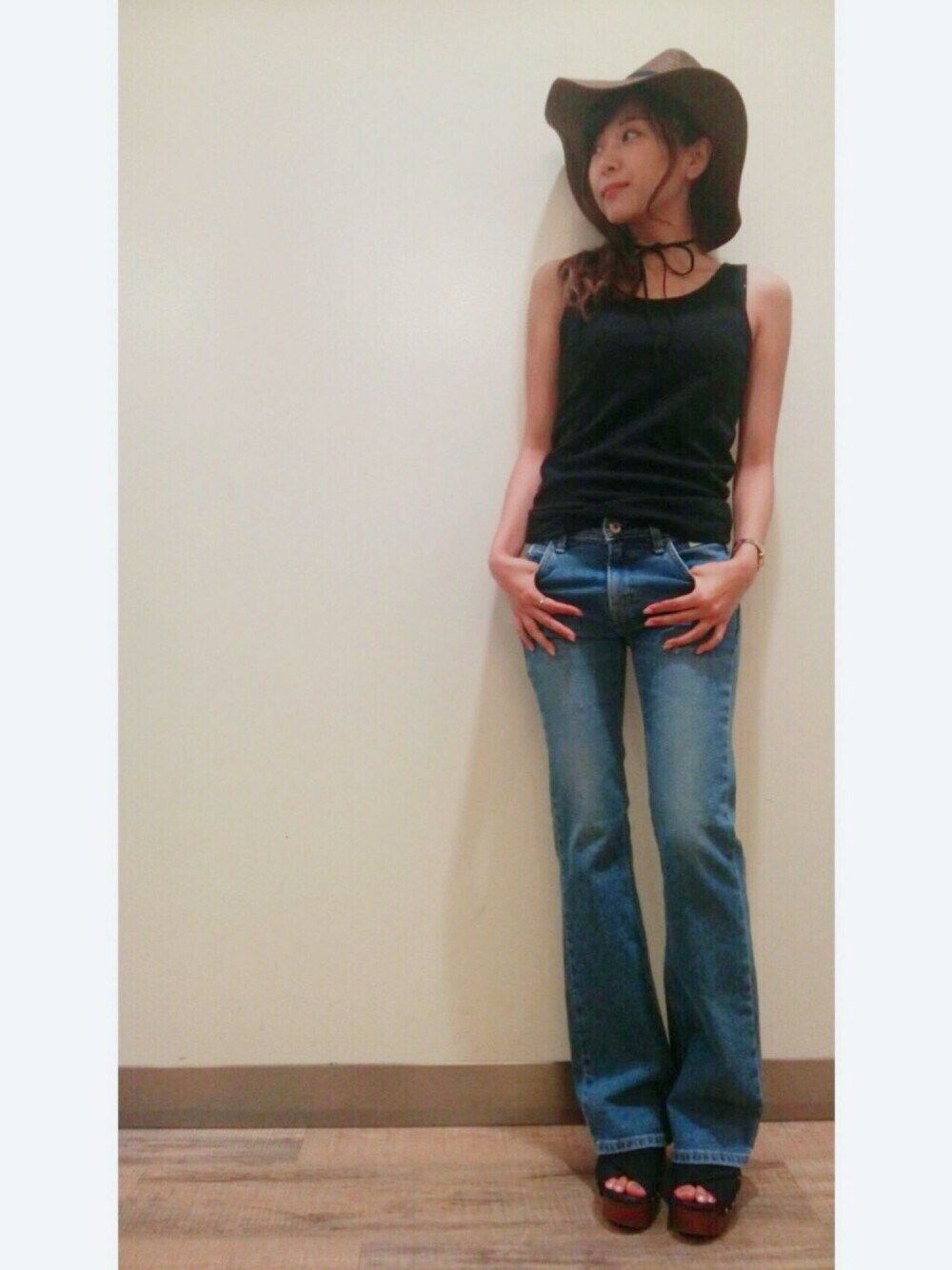 ブラック系のタンクトップ、ブラック系のサンダル、ブルー系のデニムパンツを着用したレディースの夏コーディネートの1枚目の写真