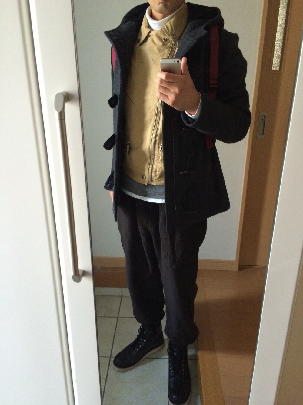 グレー系のダッフルコート、ベージュ系のベスト、ブラウン系のその他パンツを着用したメンズの冬コーディネートの1枚目の写真