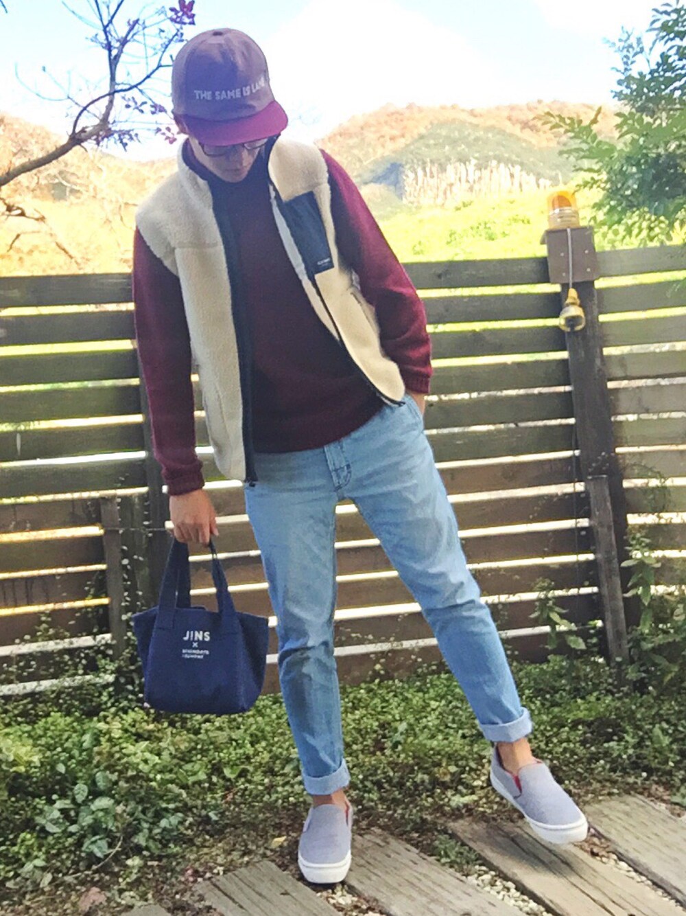 ベージュ系のベスト、レッド系のニット/セーター、ブルー系のデニムパンツを着用したメンズの冬コーディネートの1枚目の写真