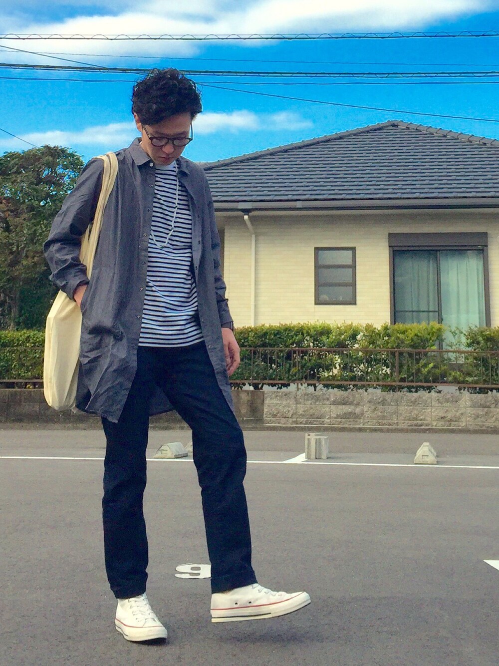 ブルー系のデニムパンツ、ホワイト系のスニーカー、ブラウン系のバッグを着用したメンズの春コーディネートの1枚目の写真