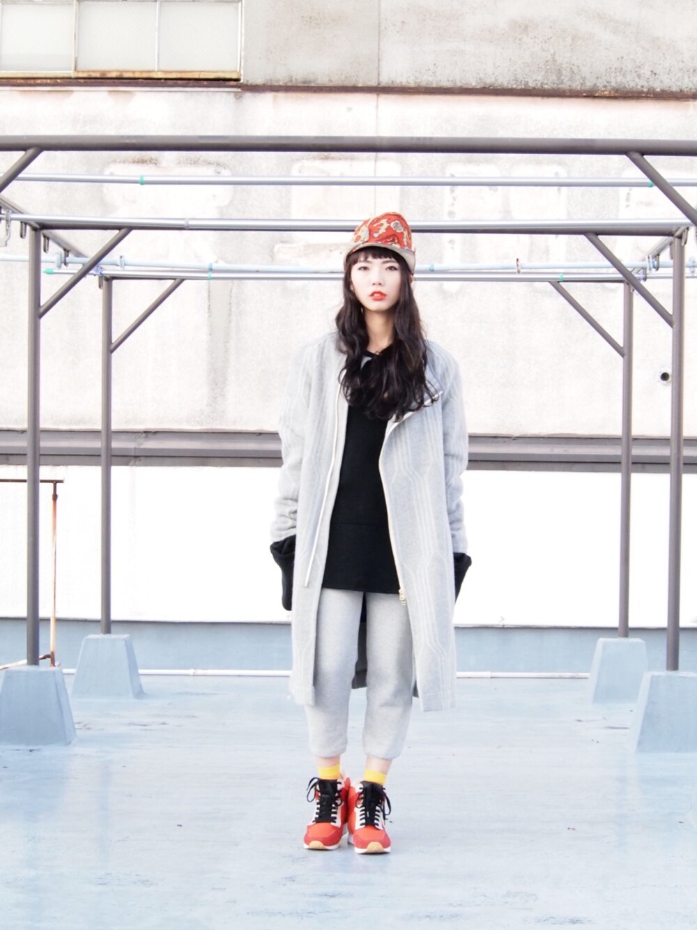 グレー系のその他アウター、レッド系のスニーカー、レッド系のキャップを着用したレディースの冬コーディネートの1枚目の写真