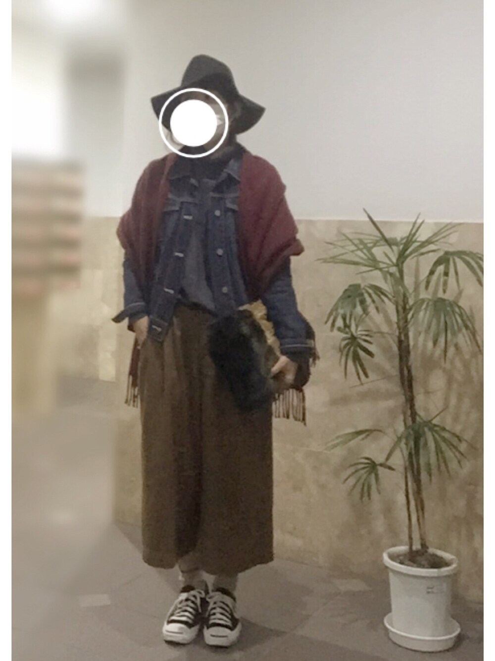 ブラック系のスニーカー、ブルー系のクラッチバッグ、ブルー系のデニムジャケットを着用したレディースの冬コーディネートの1枚目の写真