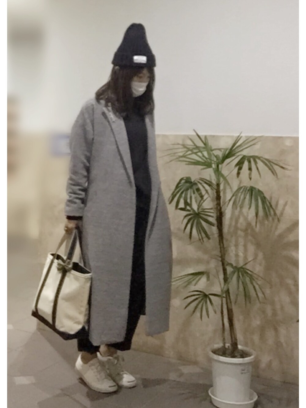 ホワイト系のスニーカー、ブルー系のトートバッグ、ブルー系の帽子を着用したレディースの冬コーディネートの1枚目の写真