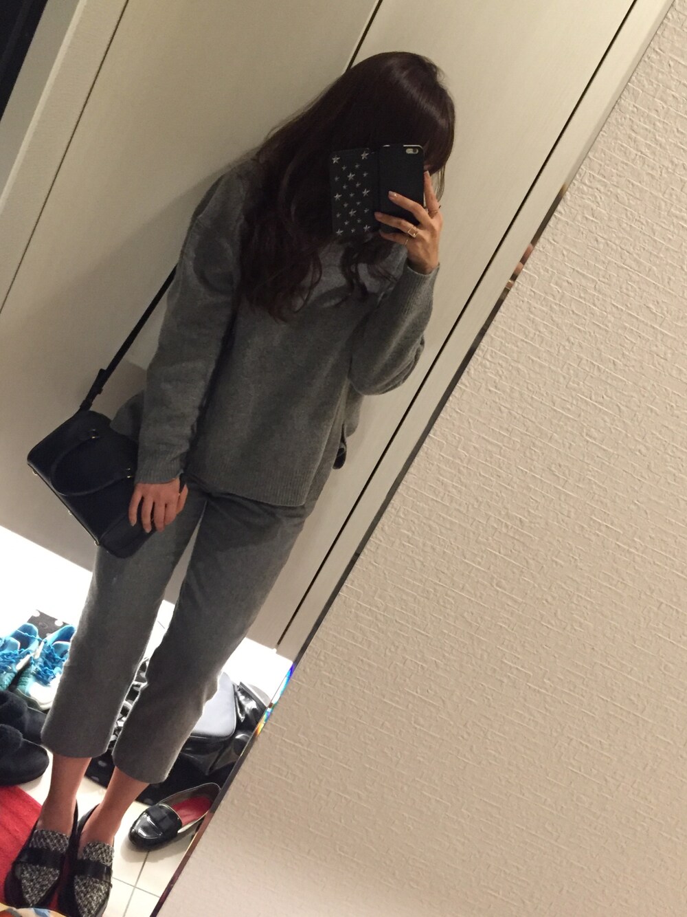 グレー系のその他パンツ、グレー系のニット/セーター、ブルー系のハンドバッグを着用したレディースの秋コーディネートの1枚目の写真