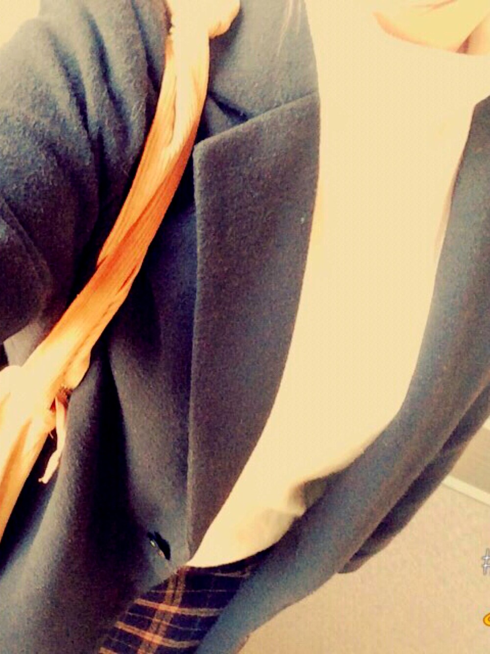 ブラック系のチェスターコート、オレンジ系のトートバッグ、ホワイト系のニット/セーターを着用したレディースの冬コーディネートの1枚目の写真