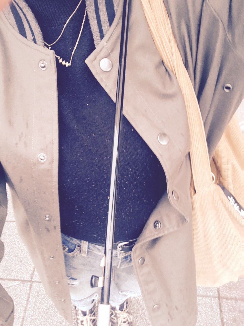 ブラック系のニット/セーター、グリーン系のブルゾン、オレンジ系のトートバッグを着用したレディースの春コーディネートの1枚目の写真