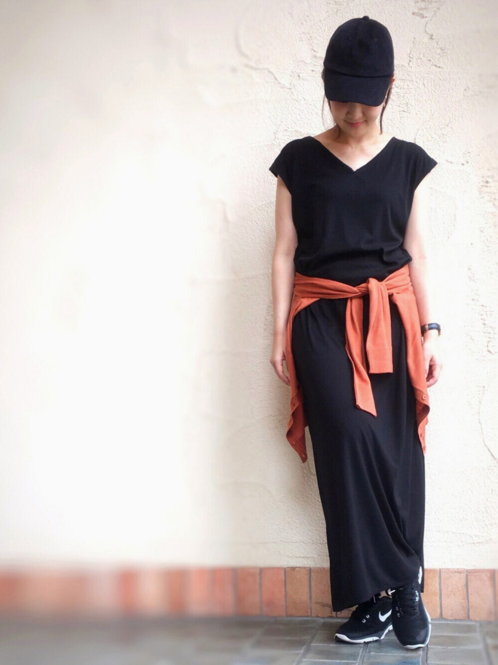 ブラック系のワンピース、レッド系のカーディガン/ボレロ、ブラック系のキャップを着用したレディースの夏コーディネートの1枚目の写真