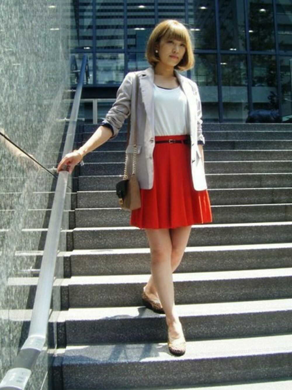 ベージュ系のテーラードジャケット、オレンジ系のスカート、ベージュ系のパンプスを着用したレディースの秋コーディネートの1枚目の写真