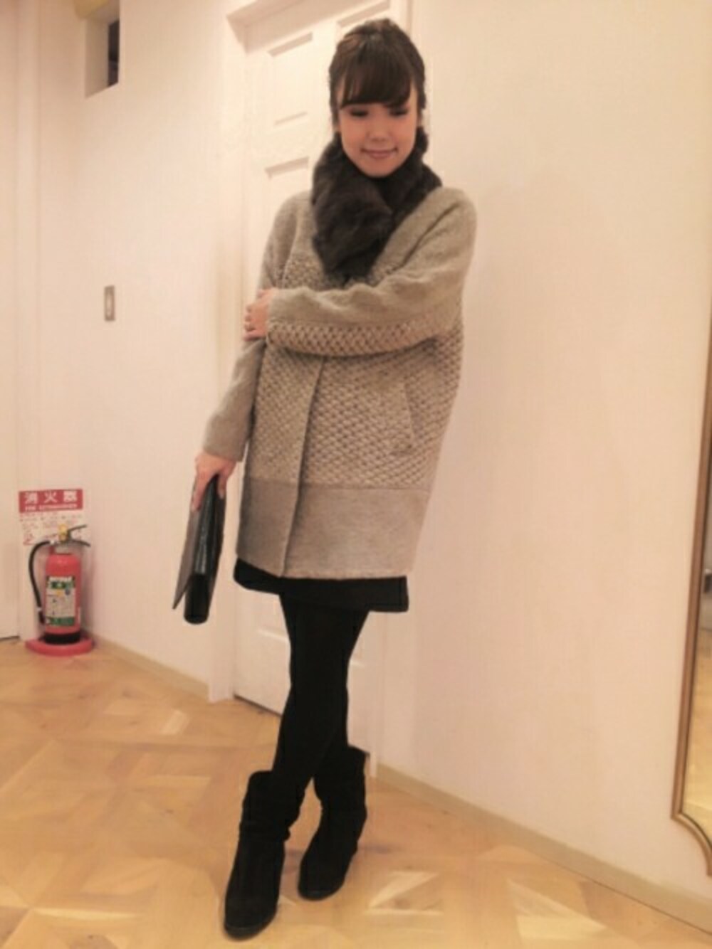 ベージュ系のその他アウター、ブラック系のワンピース、ブラック系のクラッチバッグを着用したレディースの秋コーディネートの1枚目の写真