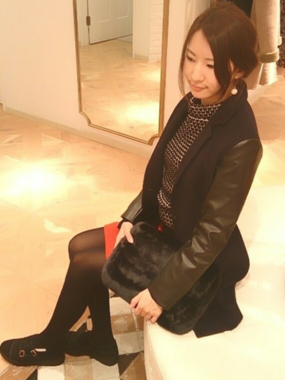 ブラック系のその他アウター、ブラック系のニット/セーター、オレンジ系のスカートを着用したレディースの冬コーディネートの1枚目の写真